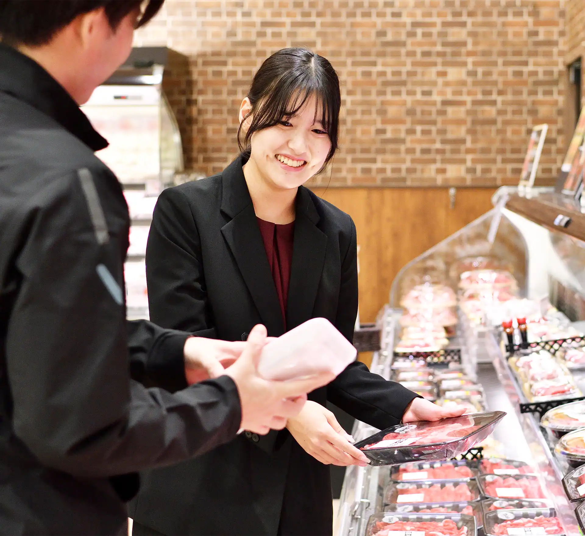 精肉売場で店員と打ち合わせをする社員