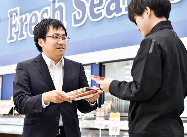 水産売場で店員とトレーを確認する社員