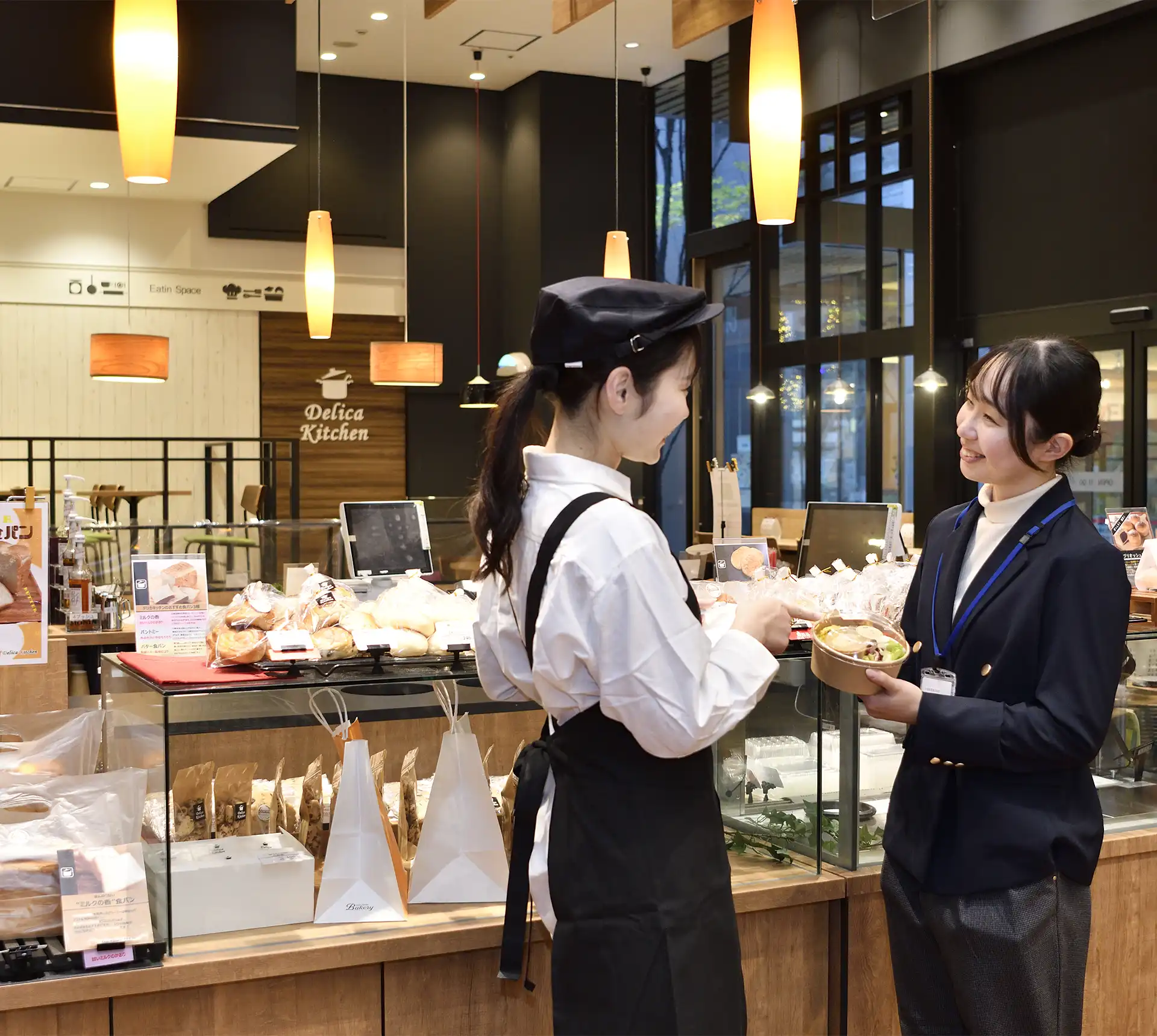 惣菜専門店でお弁当用のトレーについて打ち合わせをする店員と社員