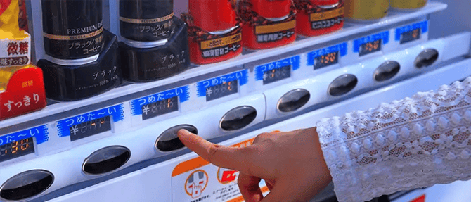 自販機で缶コーヒーを買う女性