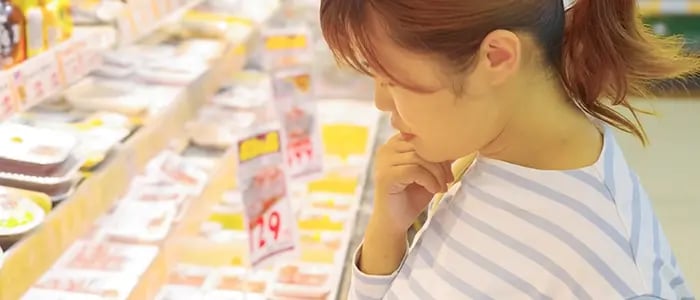 スーパーマーケットで値上がりした商品を見る女性
